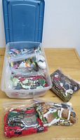 Plastic container open showing many sealed bags of colorful embroidery floss skeins inside along with additional bags of thread on the table