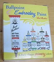 Close-up of Aunt Martha's Ballpoint Embroidery Paint 8-pack box showing vibrant primary color tubes of paint for decorating and embroidery.