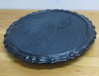 Top view of the black wooden Lazy Susan showing the scalloped decorative edge and wood grain surface.
