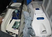 Photo of white Miracle Mate Platinum vacuum cleaner with attached long hose and manual in a clear plastic bag showing included accessories and parts.