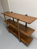 Full view of the wooden shelf showing three shelves and plastic brackets