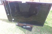 Front view of a 40 inch Samsung TV on its stand, remote control in front of base, screen is blank and reflective.