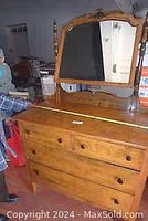 Front view of antique solid wood dresser with attached mirror reflecting room interior