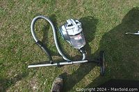 Full view of vacuum cleaner on grass showing the body, hose, wand, and nozzle attached.