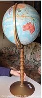 Globe showing Australia and other continents, mounted on a turned wooden stand with brass-colored base and arm
