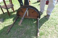 Oval half-moon oak console table flipped upside down on grass showing the underside and three turned legs.