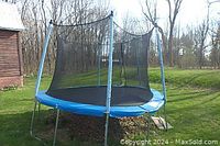 Front angle showing blue padding, black safety netting, and metal frame of the trampoline outside on grass.