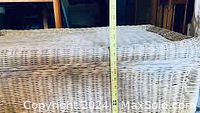 Photo showing vertical height measurement of the wicker hamper with lid by a measuring tape held against it.