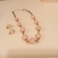Full set on white surface showing necklace with round pink rope beads and matching earrings