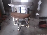 Photo showing the side view of the two antique distressed tables stacked with the demi lune table on top.
