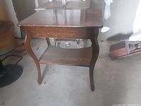 Full view of the antique wooden side table showing drawer, bottom shelf, and curved legs.
