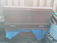 Front view of the vintage wooden chest showing overall structure and two side handles, covered partially with a blue blanket.