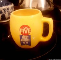 Photo of yellow ceramic mug with CBLT Five First Choice 73/74 logo on front