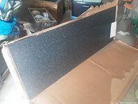 Photo of the new black speckled countertop in original packaging showing full length and texture.