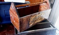 Wooden toolbox with handle showing side view, visible wear and vintage label.