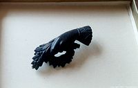 Front view of Victorian mourning brooch showing hand holding black wreath detail.