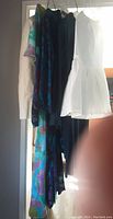 Five vintage garments hanging, including a white crinoline slip, floral patterns, and darker outerwear.