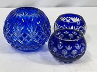 Front view of cobalt blue cut to clear crystal bowl and two votives showing the detailed cut patterns on each piece