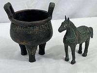 Photo showing ceramic three-legged pot and metal horse sculpture, highlighting the size and condition of both items.