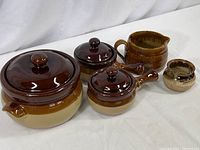 All ceramic stoneware pieces grouped together showing color and variety of shapes with lids and handles.