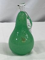 Overall front view of green Murano glass pear sculpture on white background