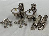 Photo showing full lot of two penguin votive holders with LED candles, two frog figurines, and pair of women's shoe figurines.