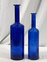 Front view of the pair of cobalt blue decorative bottles showing their height difference and color.