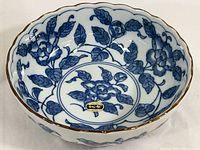 Top view showing detailed blue floral design and scalloped rim with brown/gold edge, Utsuwa Japan sticker visible.