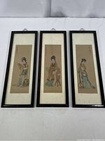 Three vertical framed watercolor silk paintings of Chinese women, side by side on white surface.
