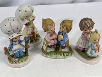 Four vintage hand painted Lefton china figurines grouped together showing various designs and details.