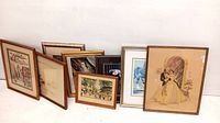 Multiple framed prints including a variety of scenes leaning against a wall.