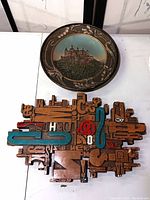 Photo showing the ceramic Hohenzollern Castle wall plate above a ceramic letter collage wall display on a white surface.