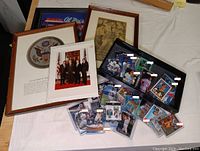Overview photo showing Presidential Seal plaque, several framed photos, and a display case with assorted football and baseball cards scattered on table