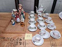 Overview photo showing all demitasse and espresso cups with saucers and assorted Victorian figurines and keepsakes on a wooden tray.