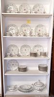 Full shelving display showing assorted Johann Haviland plates, tea cups, saucers, and serving ware with floral pattern and gold trim.