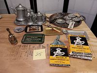 Full lot overview showing pewter teapot, pitchers, branded metal trays, various vintage and promotional items including damper quadrant sets and utensils