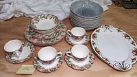 Photo shows various pieces of dishware including floral motif teacups, saucers, plates, blue-gray Denby bowls, and floral Royal Albert platter.