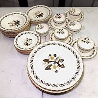 Full display of Royal Worcester Engadine china set showing plates, teacups, sugar bowls, and creamers with floral pattern and gold trim.