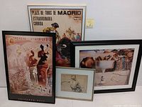 Group of four framed art and event posters showing Salvador Dali prints, Spanish bullfighting poster, and Ruben's classical print.