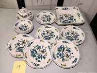 Full view of 6 luncheon plates, 4 bowls, 6 plates, and sugar bowl with floral and bird design.