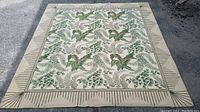 Full view of the vintage rectangular rug showing the botanical green leaf pattern and beige geometric border.
