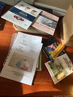 Photo showing assortment of art books by Pat Lentine, watercolor and sketch pads including Strathmore brand, and Prismacolor watercolor pencils with color blender pencil, along with a lap desk.