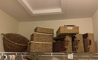 Photo showing variety of woven baskets on shelf including picnic basket, rectangular flip-top and smaller baskets