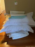 Stack of bedding items including pillows, quilt, comforter and moisture proof pad.