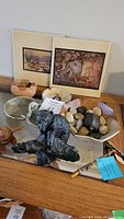 Lot showing framed artwork behind pottery bowls, carved bear sculpture in foreground, assorted river stones, and tool-marked stick with COA.