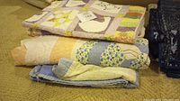 Photo showing stacked quilts with visible duck and ladies applique on top quilts.