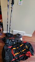 Photo showing two Urban Pole 300 hiking sticks and several bags including the Jack Wolfskin backpack and fanny packs, plus ball caps.
