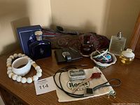 Overview of mens collection on wooden dresser including ties, wallet, watch, perfumes, jewelry, and mints.