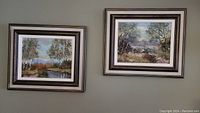 Two framed landscape paintings hanging side by side on a wall, showing natural scenes with trees and water.