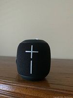 Front view of black Ultimate Ears Wonderboom speaker showing large volume plus and minus buttons on black mesh fabric body.